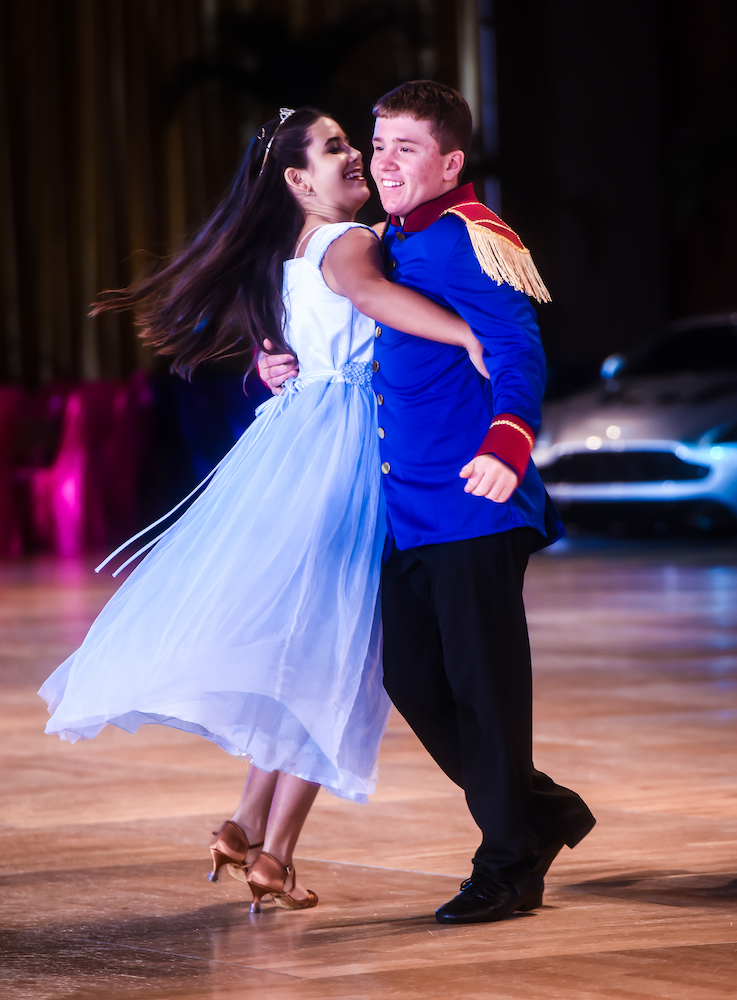 A teen couple in Cinderella and prince costumes performing a showcase routine